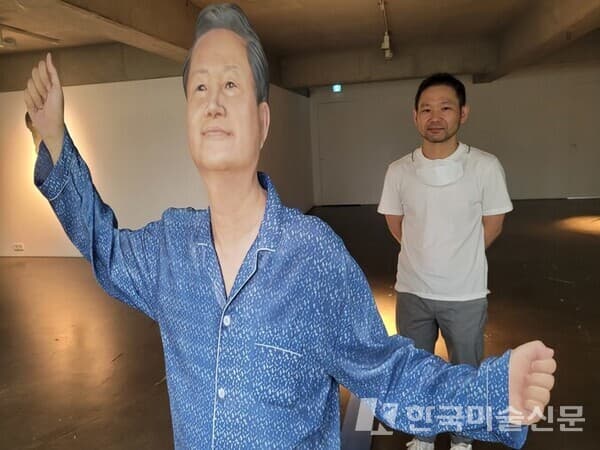 예화랑 3층 전시장의 신작 인물상 뒤에 나란히 서 있는 이환권 작가. 장인어른의 기지개 장면을 납작하게 뜬 그림자 형상의 합성수지로 빚어낸 작품이다.