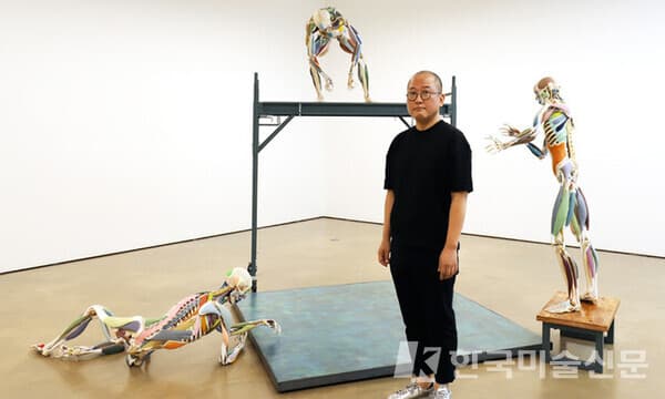&lsquo;조각가들&rsquo; 앞에 서 있는 최수앙 작가. (출처 = 학고재 제공)