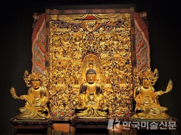 경북 예천군 용문사 대장전에 전해지는 &lsquo;목각아미타여래설법상&rsquo;(국가지정보물).가로 215㎝, 세로 261㎝의 목각아미타여래설법상은 직사각형 모양 좌우에 구름무늬 조각을 덧붙여 장엄하게 장식했다. 17세기 중반부터 18세기 초까지 활동한 거장 단응을 비롯한 조각승 9명이 일일이 나무판을 깎고 다듬어 불화 같은 도상을 구현한 목각탱 작품이다. 목조아미타여래삼존좌상 가운데가 본존불인 아미타여래좌상, 왼쪽 관세음보살 좌상, 오른쪽이 대세지보살 좌상이다. 국립중앙박물관 제공
