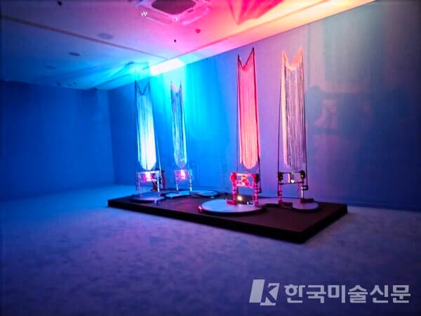 권병준, 중심에서 피어나는; 잠재태의 황금꽃, 2025, 혼합 매체(모터, 전자석, 알루미늄 프로파일, 컨트롤보드, 3D, 프린터로 제작한 PLA, 낚싯대, 장식용 술, 운판, 컴퓨터), 각 400 &times; 300 &times; 350 cm(아해, 로봇 무당 4점), 가변 크기